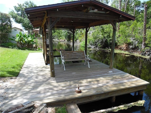 dock area with a lawn and a water view