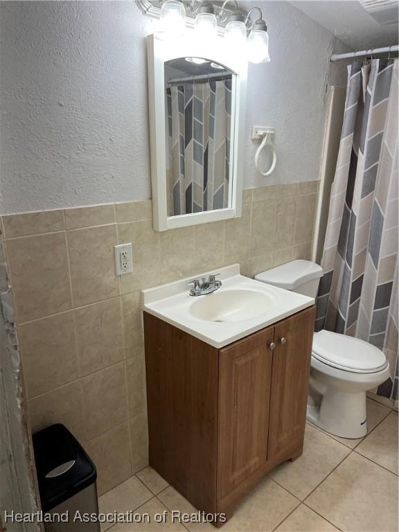 bathroom featuring vanity, toilet, tile patterned flooring, and tile walls