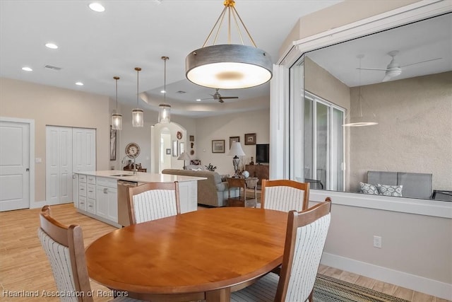 dining room featuring ceiling fan, sink, and light hardwood / wood-style floors