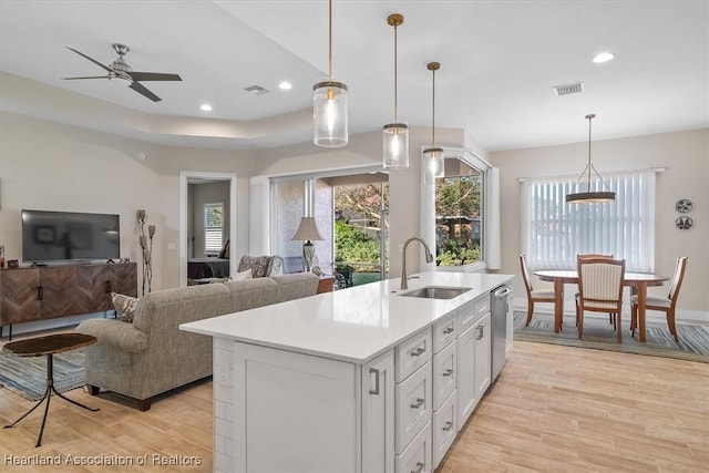 kitchen with sink, decorative light fixtures, dishwasher, and a center island with sink