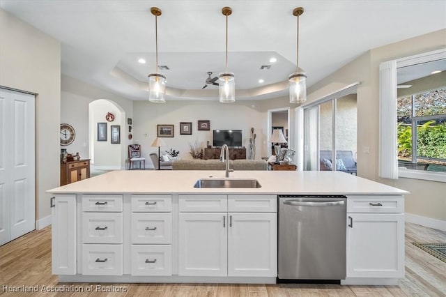 kitchen with stainless steel dishwasher, a raised ceiling, sink, and white cabinets