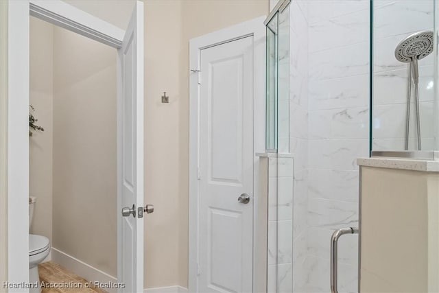 bathroom with wood-type flooring, a shower with shower door, and toilet