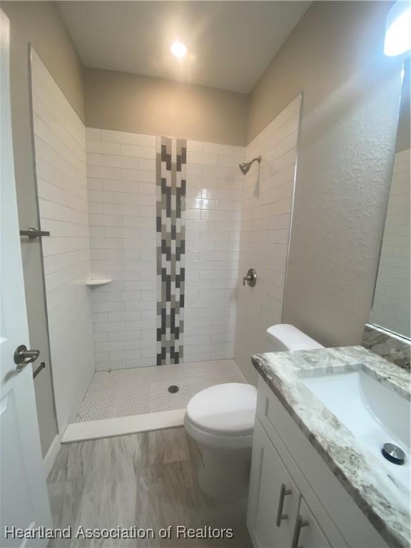 bathroom featuring tiled shower, vanity, and toilet