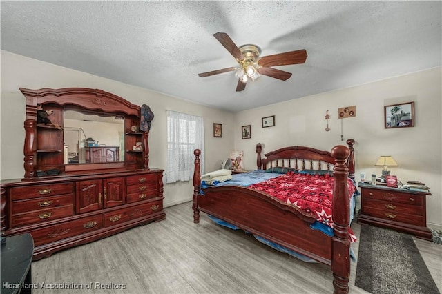 bedroom featuring light wood-type flooring, a ceiling fan, and a textured ceiling