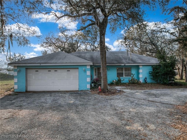 single story home featuring driveway, an attached garage, and stucco siding