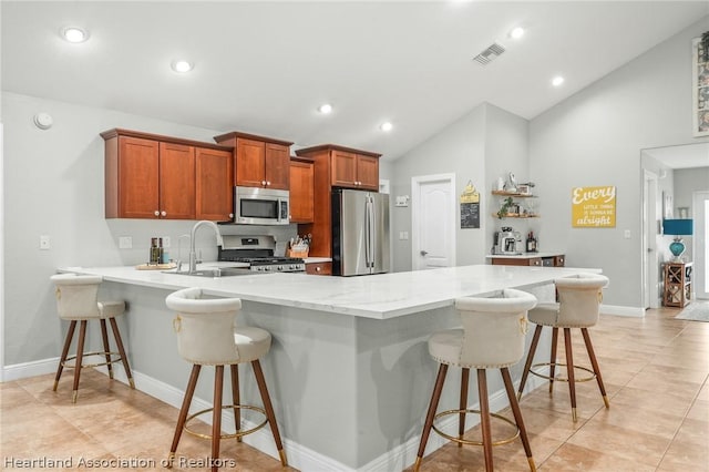 kitchen with sink, stainless steel appliances, vaulted ceiling, a breakfast bar, and light tile patterned floors