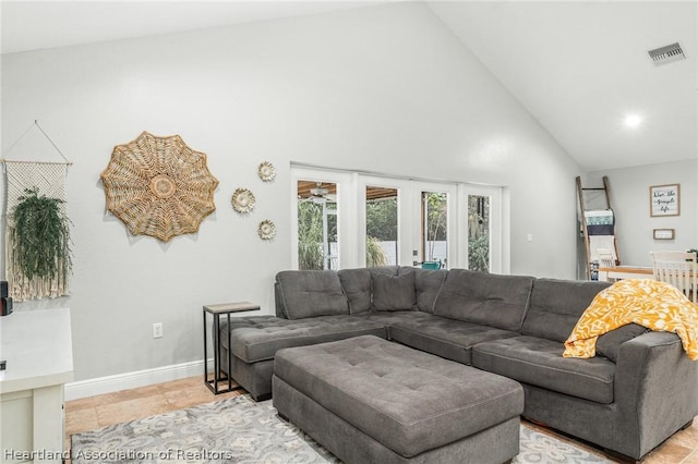 tiled living room featuring high vaulted ceiling and french doors