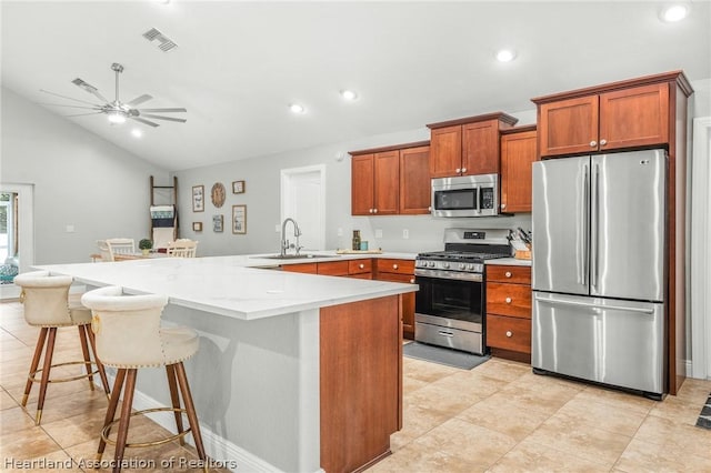 kitchen with appliances with stainless steel finishes, a kitchen breakfast bar, ceiling fan, sink, and lofted ceiling