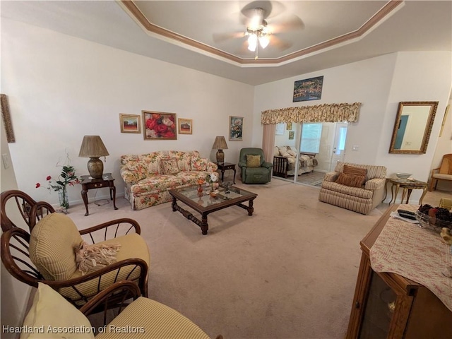 living room with a tray ceiling, ceiling fan, and carpet floors