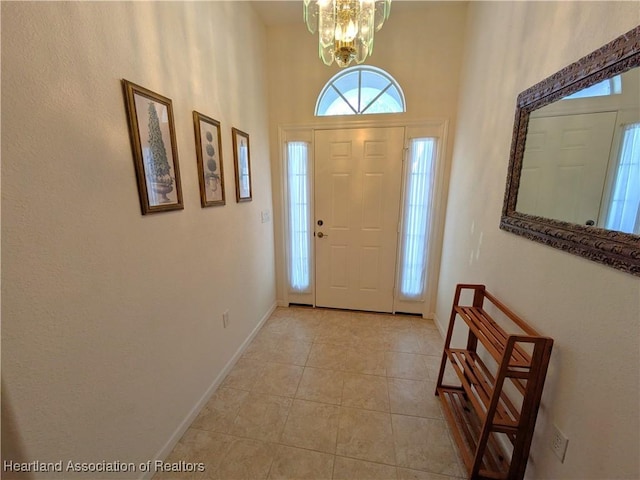 entrance foyer featuring a towering ceiling, light tile patterned floors, and an inviting chandelier