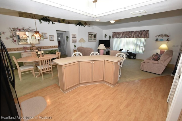 kitchen with light brown cabinets, decorative light fixtures, refrigerator, and light hardwood / wood-style floors