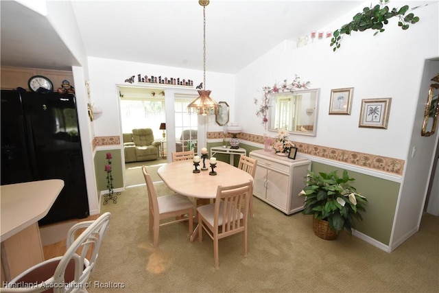 carpeted dining room with an inviting chandelier