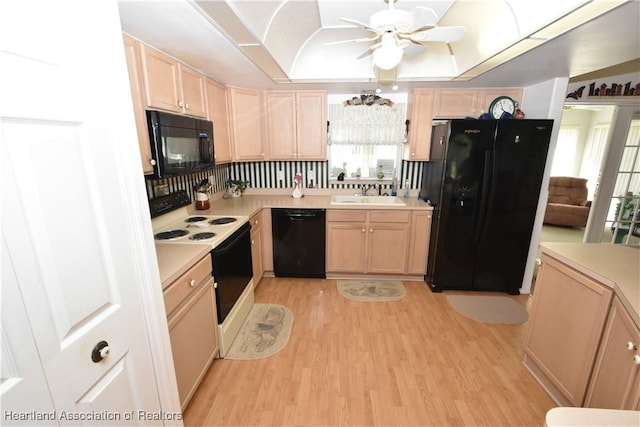 kitchen featuring light hardwood / wood-style floors, black appliances, light brown cabinets, a tray ceiling, and sink