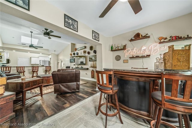 bar featuring stainless steel refrigerator and lofted ceiling