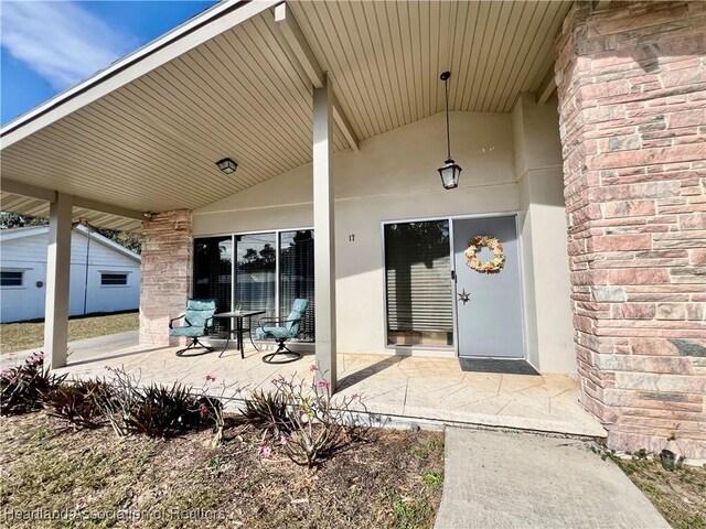 entrance to property featuring a patio area and brick siding