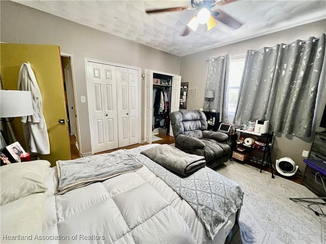 bedroom with wood finished floors, ceiling fan, and two closets