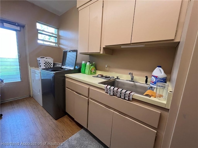 laundry room with washer and clothes dryer, light hardwood / wood-style floors, cabinets, and sink