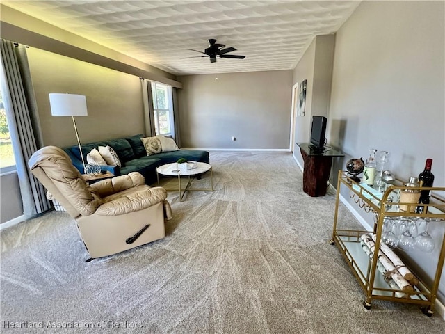 carpeted living area featuring a ceiling fan and baseboards