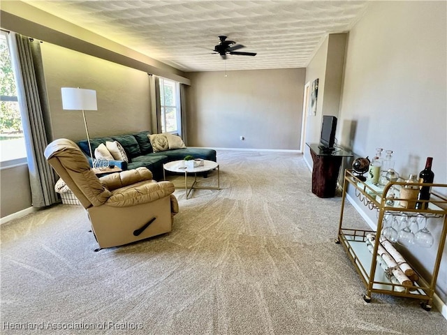 living room with light carpet, a ceiling fan, and baseboards