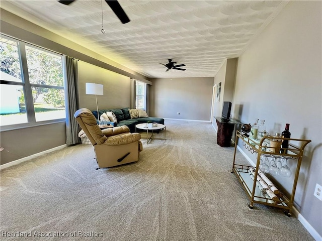 living room featuring a ceiling fan, light colored carpet, and baseboards