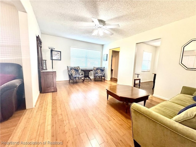 living room featuring a textured ceiling, light hardwood / wood-style flooring, ceiling fan, and plenty of natural light