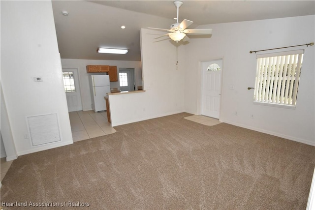 unfurnished living room featuring vaulted ceiling, light carpet, and ceiling fan