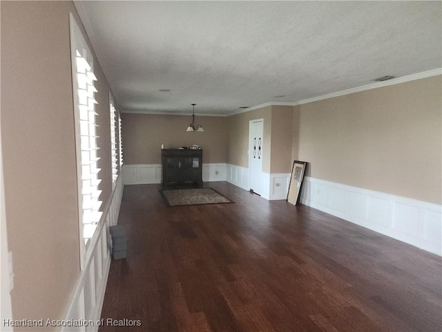 unfurnished living room featuring dark wood-style flooring, wainscoting, and ornamental molding