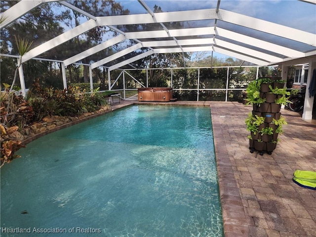 outdoor pool with a hot tub, a patio, and a lanai
