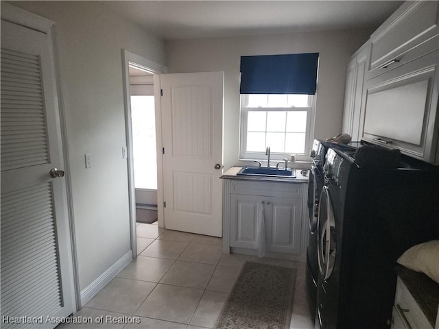 laundry room featuring washing machine and clothes dryer, cabinet space, and light tile patterned floors