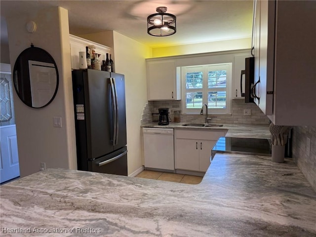 kitchen with white cabinets, black appliances, backsplash, and a sink