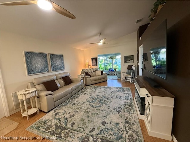 living room with visible vents, wood finished floors, a ceiling fan, and lofted ceiling