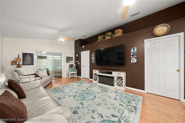 living room featuring ceiling fan, baseboards, light wood-style flooring, and visible vents