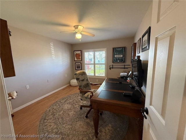 office area with light wood-type flooring, a ceiling fan, and baseboards