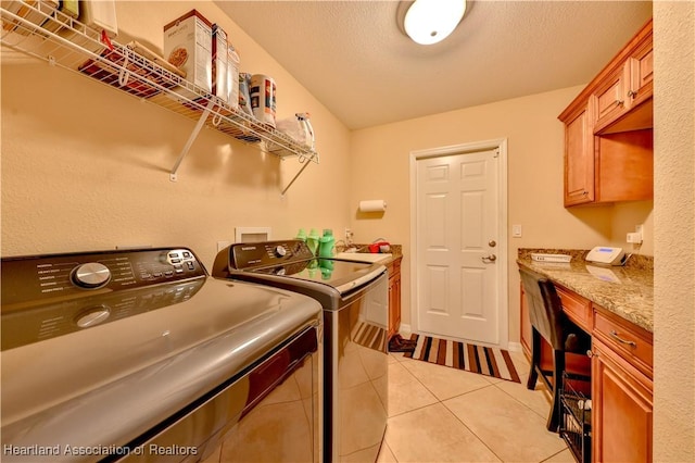 clothes washing area featuring cabinets, light tile patterned flooring, washer and dryer, and a textured ceiling