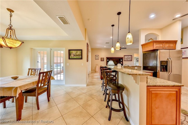 kitchen featuring french doors, hanging light fixtures, light stone countertops, light tile patterned flooring, and stainless steel fridge with ice dispenser