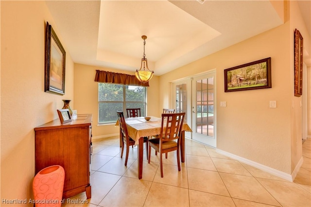 tiled dining room featuring a tray ceiling and french doors