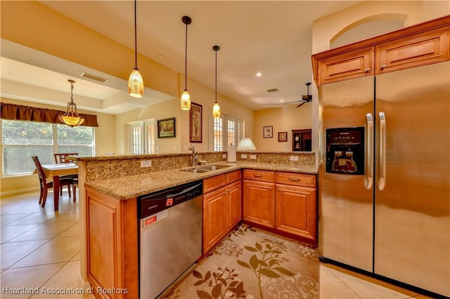 kitchen with appliances with stainless steel finishes, light stone counters, ceiling fan, sink, and pendant lighting