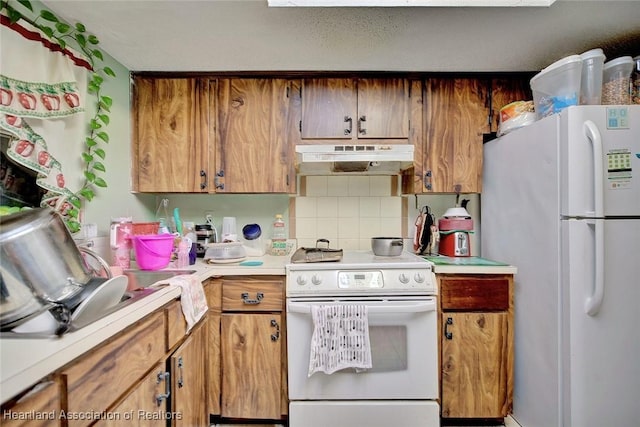 612 Denise Ave, Sebring, FL 33870 - kitchen with light countertops, white appliances, tasteful backsplash, under cabinet range hood, and brown cabinetry
