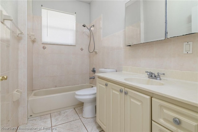 full bathroom with vanity, tile patterned flooring, tiled shower / bath combo, toilet, and tile walls