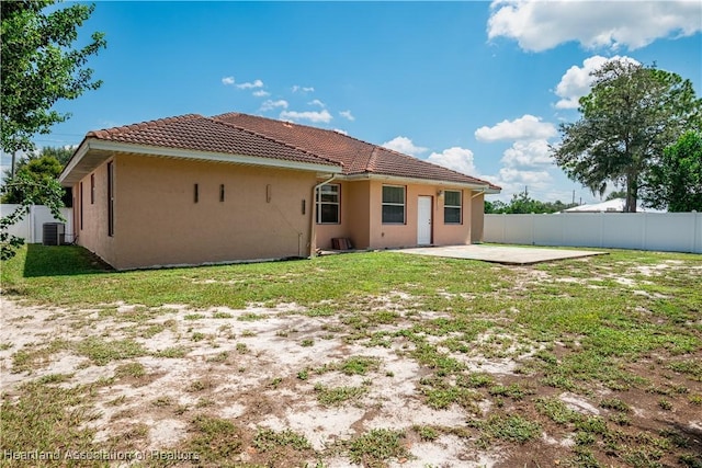 rear view of property featuring a yard, cooling unit, and a patio area