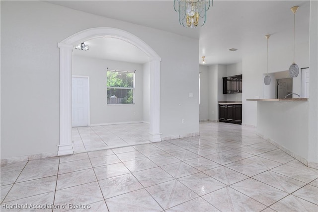 tiled empty room featuring a notable chandelier