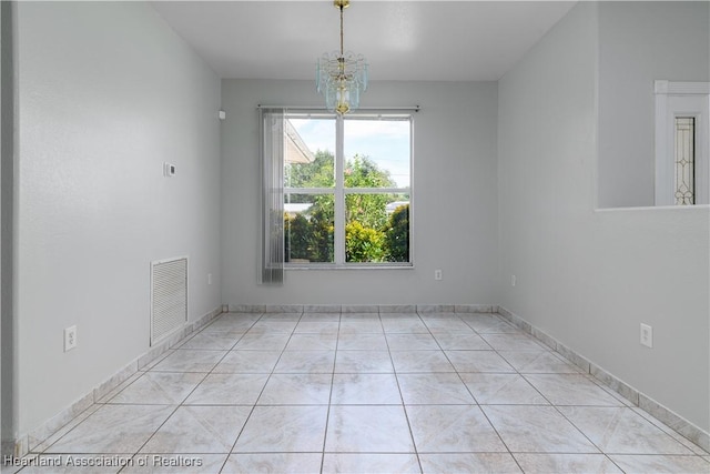 tiled spare room featuring a notable chandelier