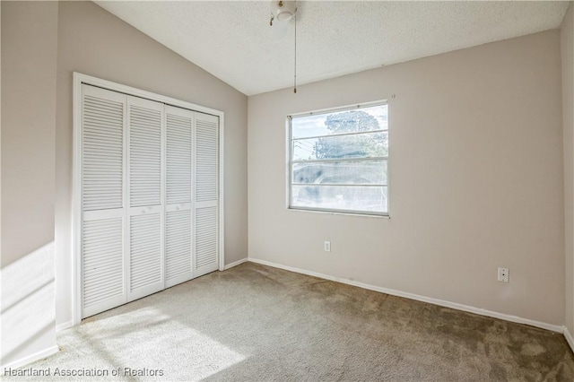 unfurnished bedroom featuring carpet flooring, vaulted ceiling, and a closet