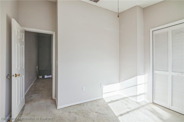 unfurnished bedroom with light colored carpet and a closet