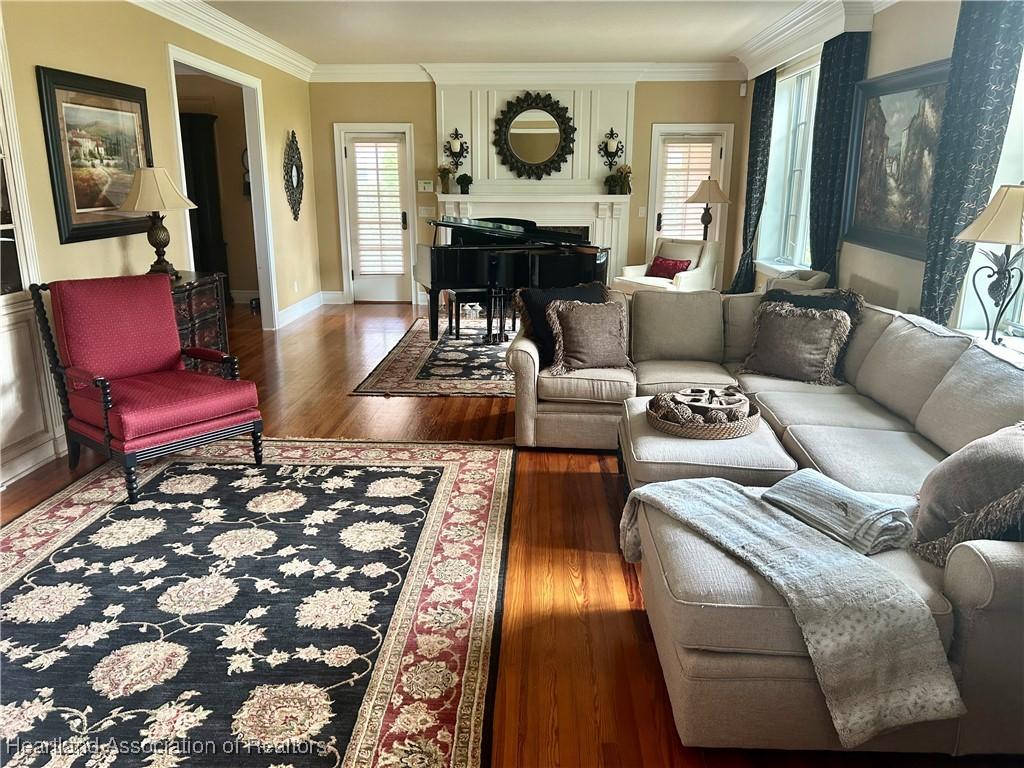 1831 Lakeview Dr, Sebring, FL 33870 - living room featuring healthy amount of natural light, wood finished floors, a fireplace, crown molding, and baseboards