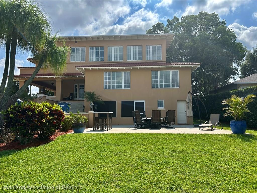 1831 Lakeview Dr, Sebring, FL 33870 - back of house with stucco siding, a patio, and a lawn