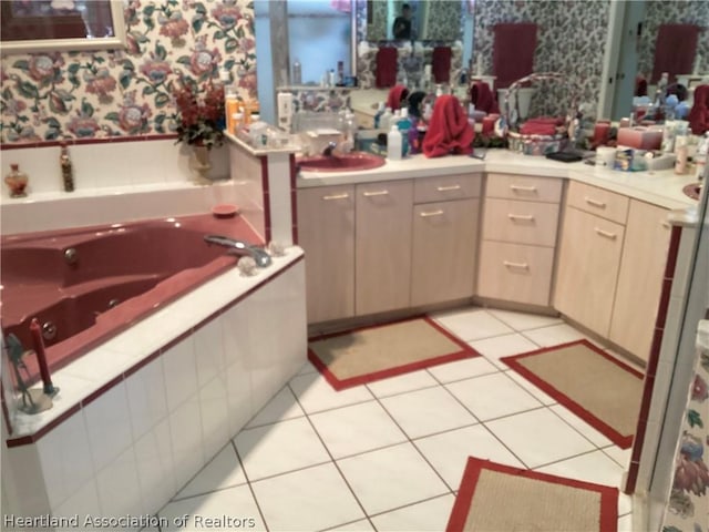 bathroom with tile patterned floors, a relaxing tiled tub, and sink