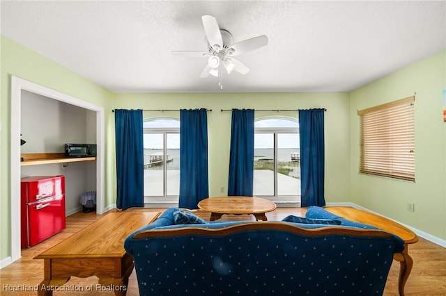 bedroom with baseboards, ceiling fan, multiple windows, and wood finished floors