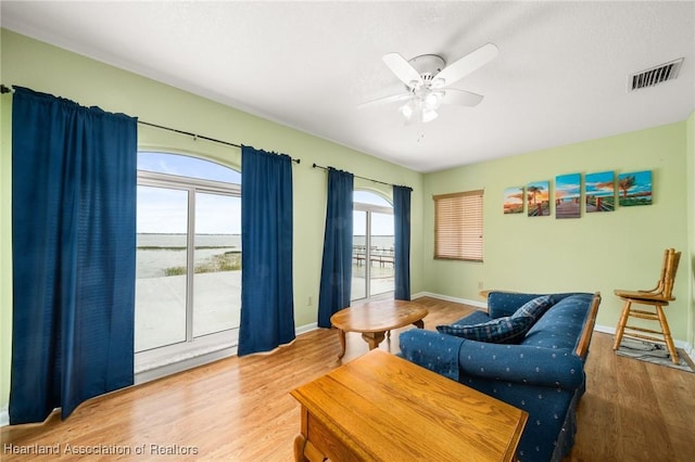 living room with visible vents, baseboards, ceiling fan, and wood finished floors