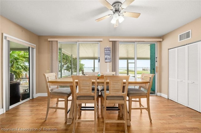 dining room with light wood-type flooring, baseboards, visible vents, and a healthy amount of sunlight